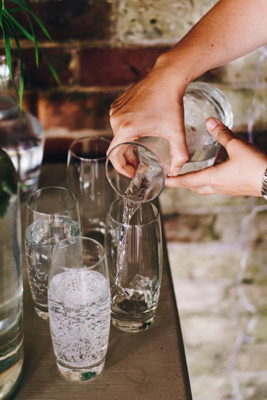 a person is pouring some water in to some glasses