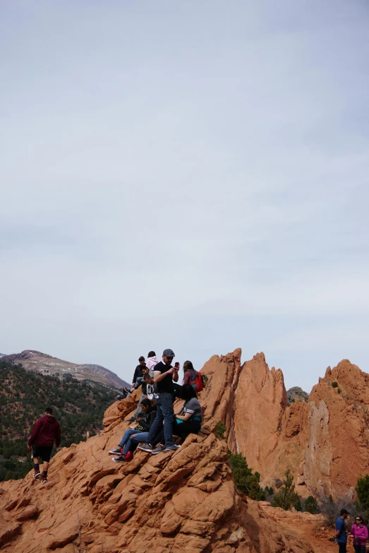 people on top of large rock formation with sky above