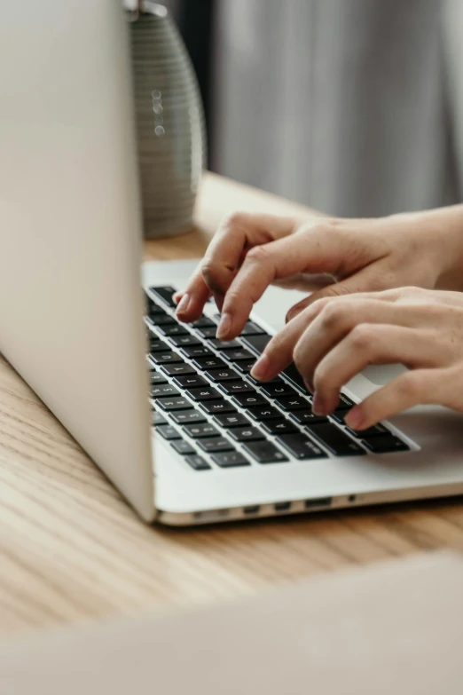 a woman is typing on a laptop keyboard