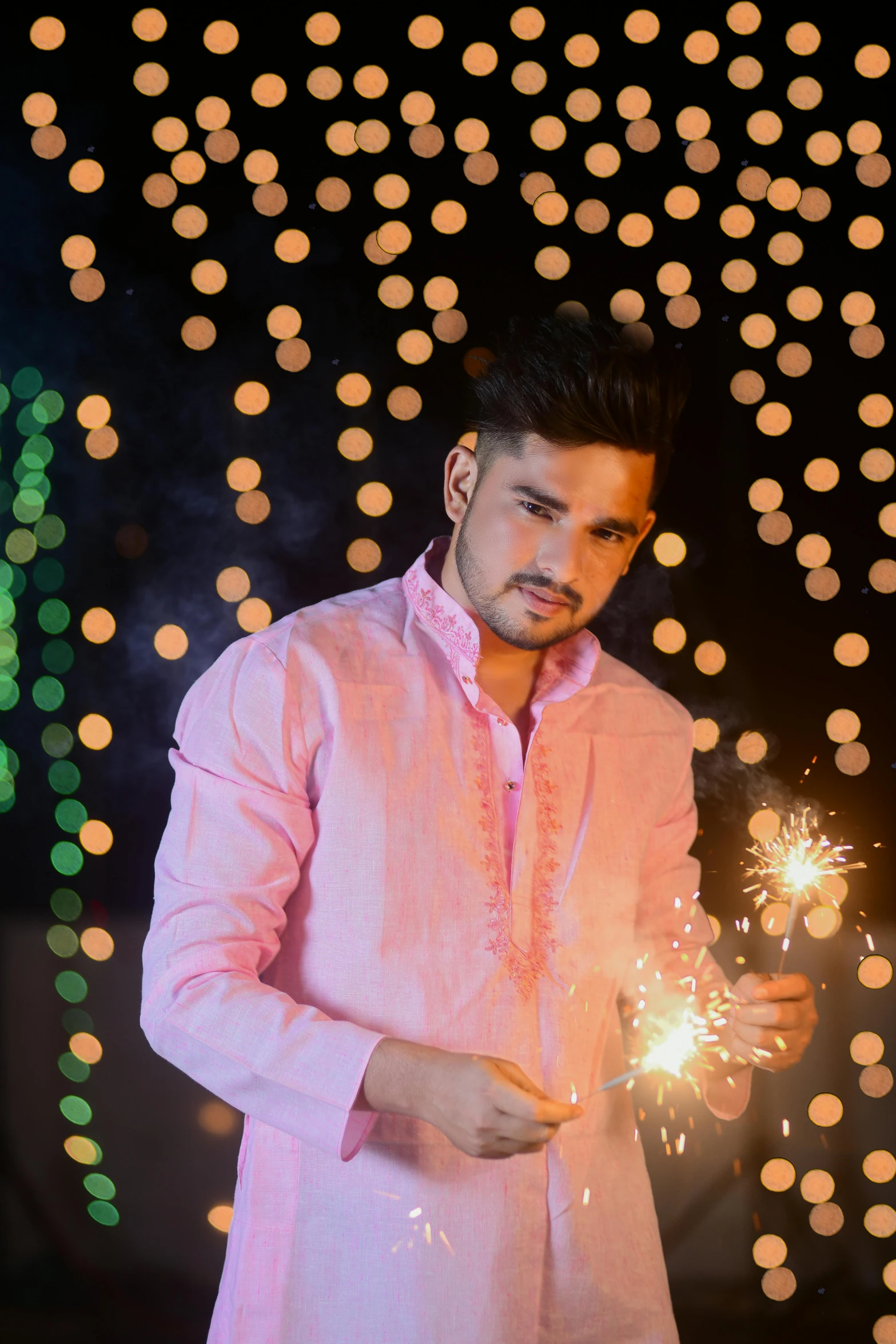 a man in pink shirt holding a lit sparkler