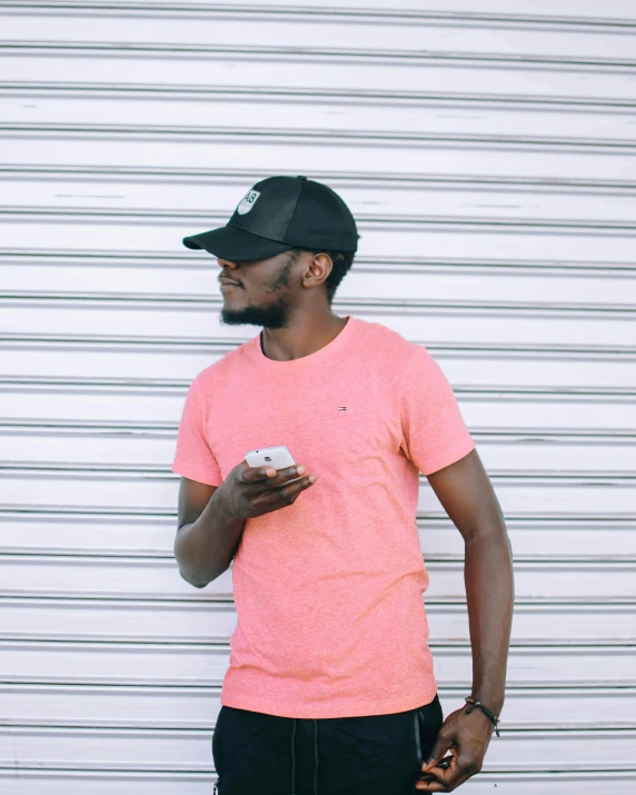 a black man wearing a neon pink tshirt and holding a white object