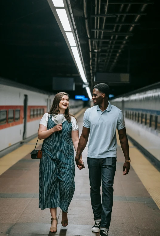 a man and woman walking on a subway platform