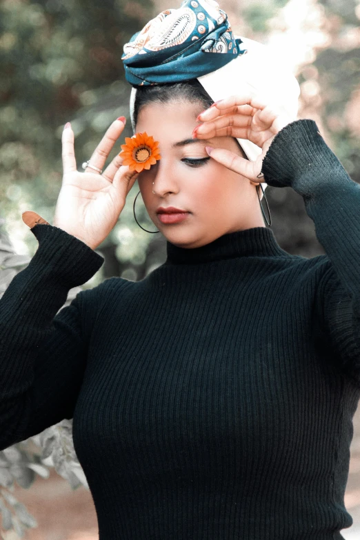 the woman is covering her eyes and is holding an orange flower