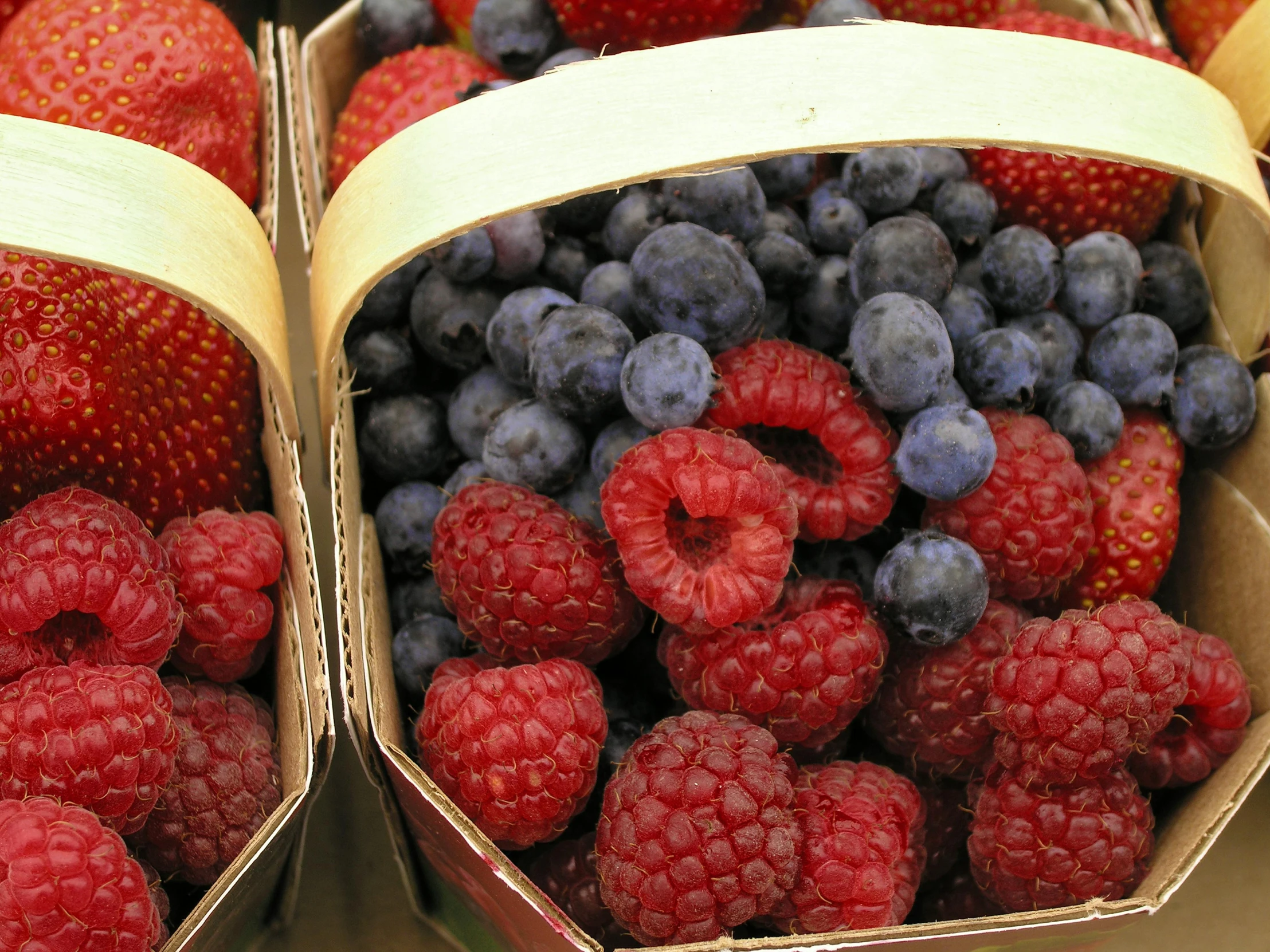 two open cardboard boxes full of berries and blueberries