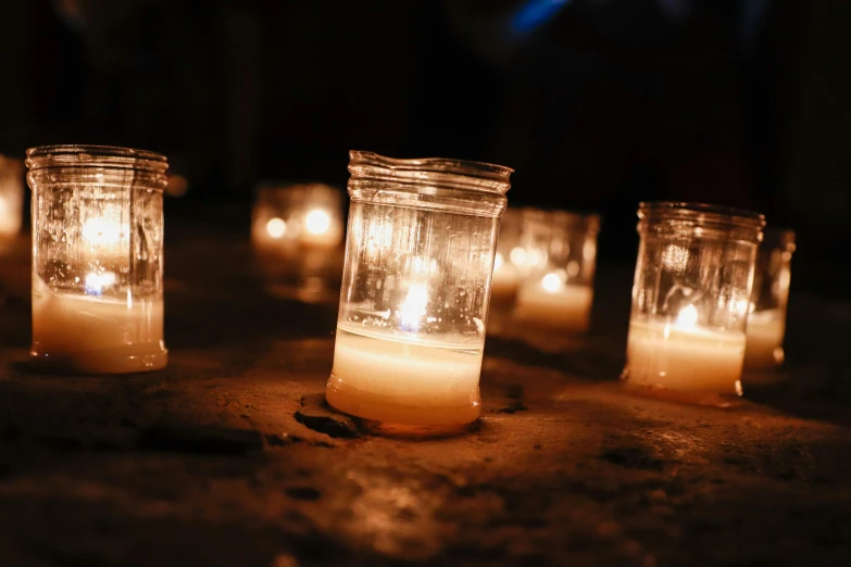 candles are in glass jars with some lit on top