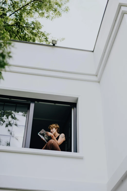 the man is holding his racket while looking out the window