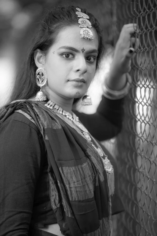 a girl in a sari looking out of a net door