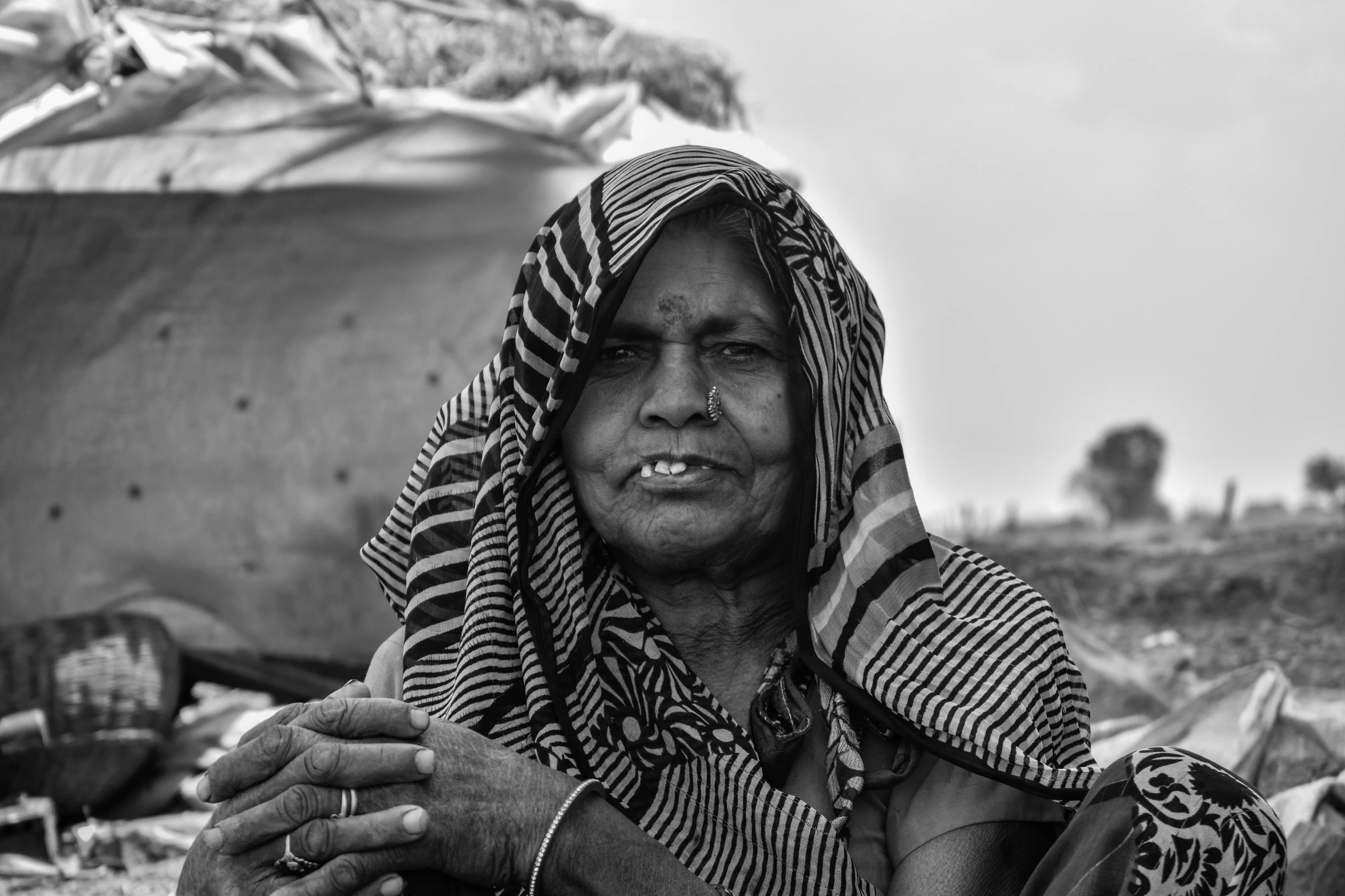 an old woman sits on the sand in her desert outfit