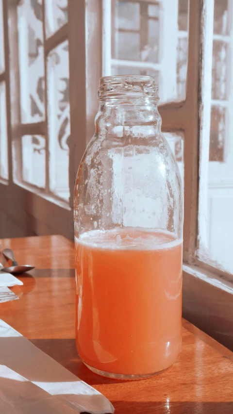 a glass bottle filled with orange liquid on top of a table