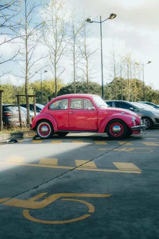 a pink vintage car is parked in front of a parking meter