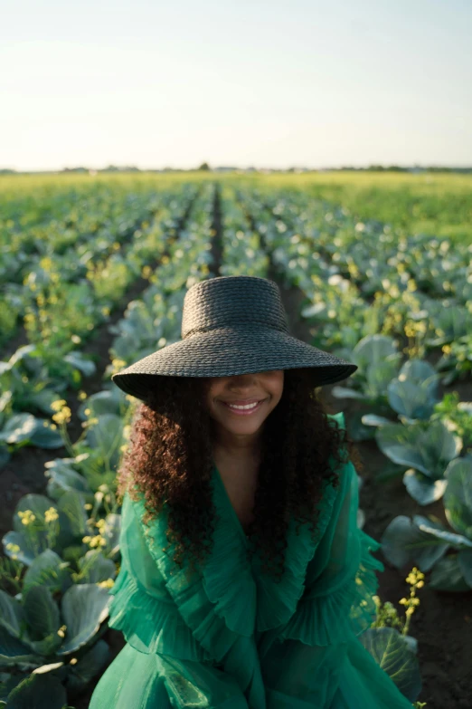 a woman standing in the middle of a field with crops