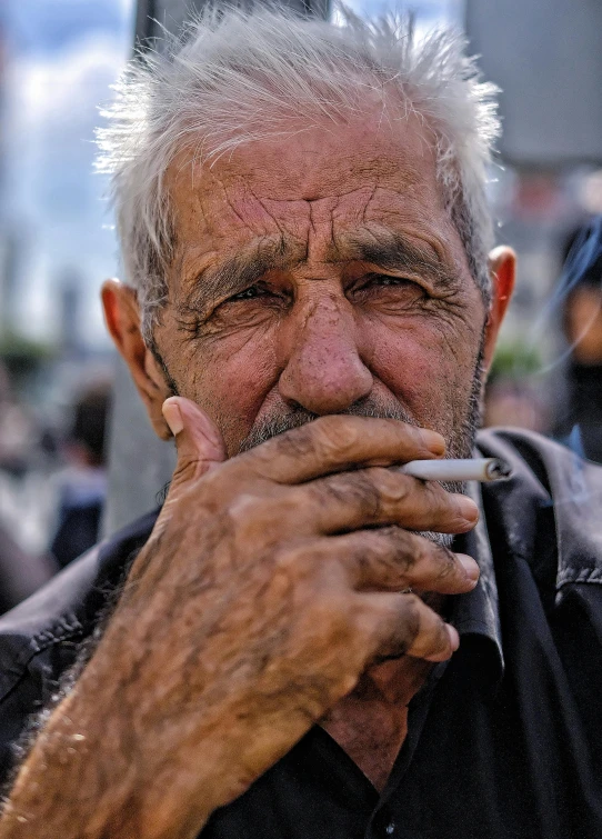 a man with long white hair is smoking a cigarette