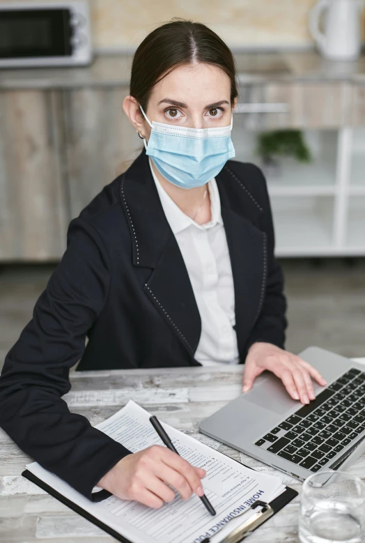 a business woman with face mask working on a laptop