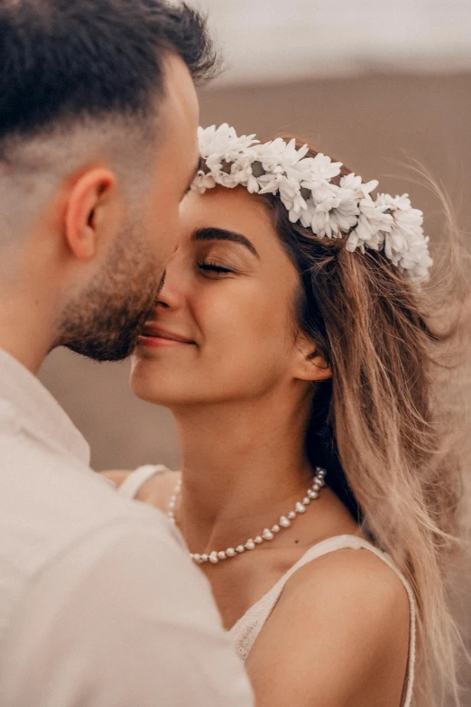 a bride and groom wearing a flower wreaths pose for a po