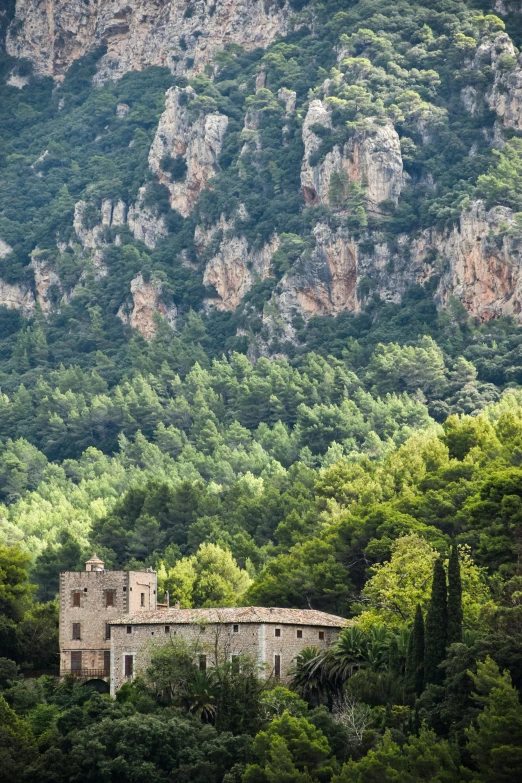 an old stone house sitting on top of a green hillside