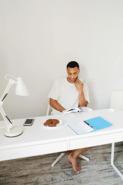 a man sitting at a white desk with his feet crossed