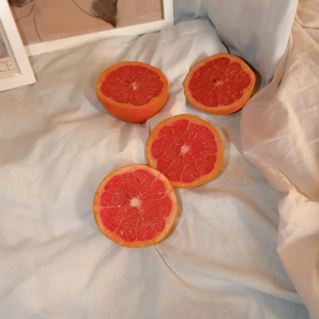 three gfruit slices lie on a piece of cloth near an empty picture frame