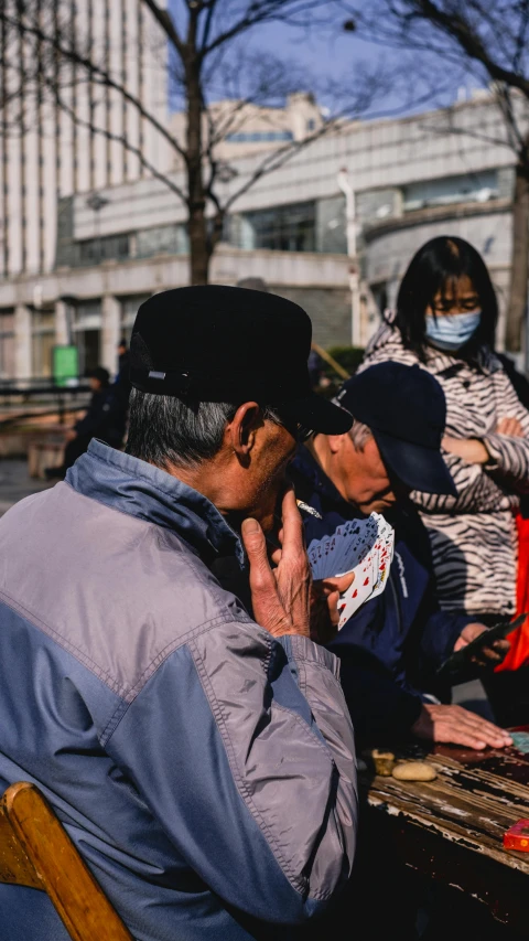 a man talks on a cell phone while sitting in a chair near others