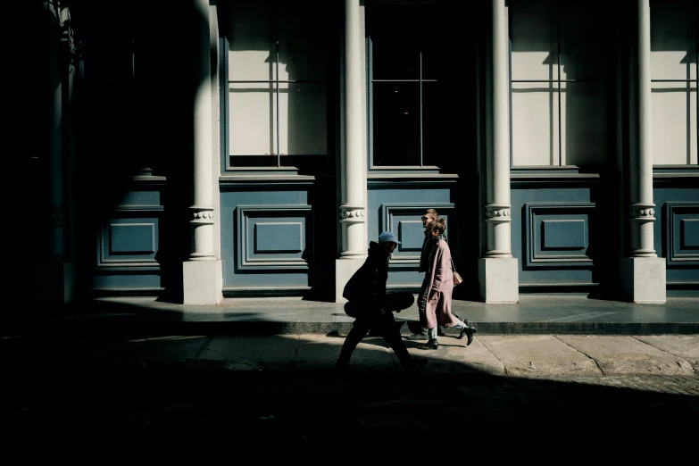 woman walking down a sidewalk, with a large building in the background