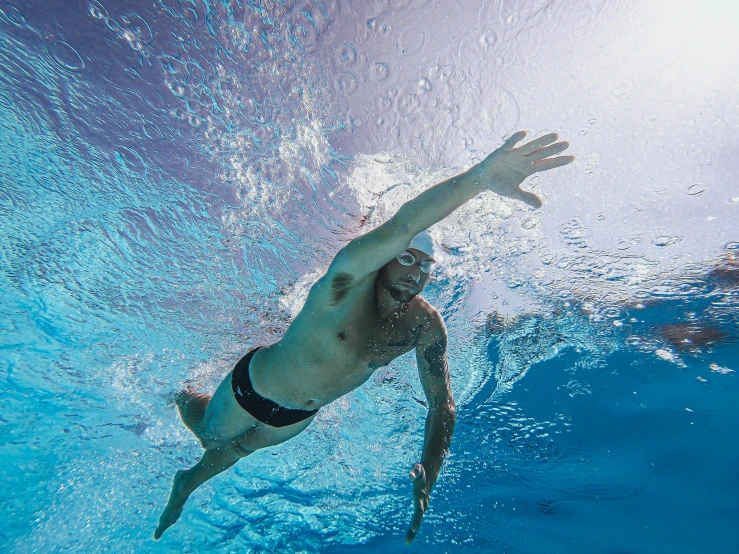a man in a swimming suit swims under water