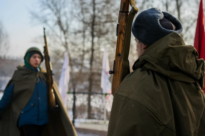 two people holding guns in their hands standing next to flags