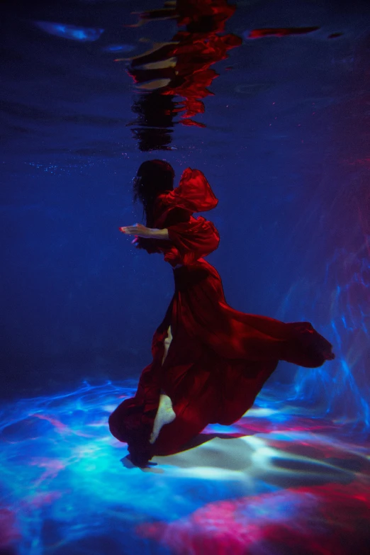 a woman is seen underwater in red clothing
