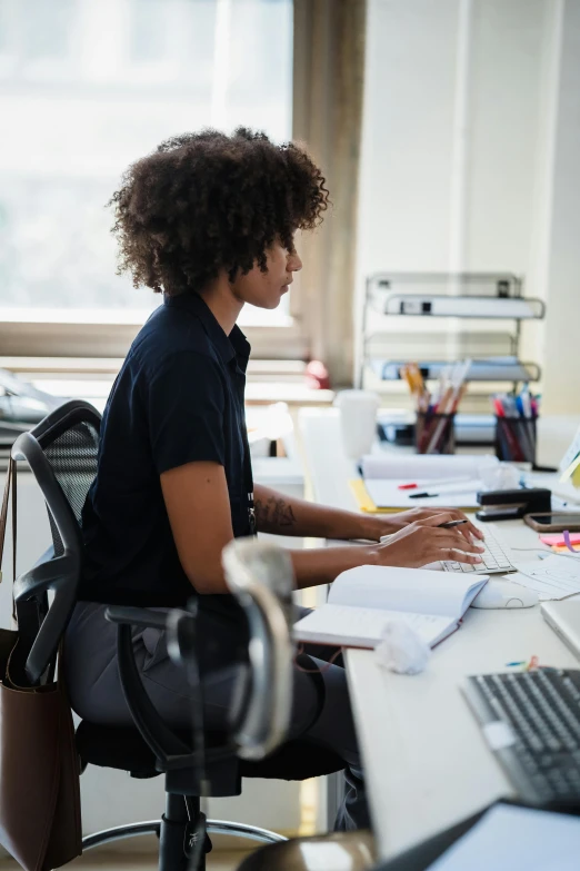 a woman is working on a computer with an afro