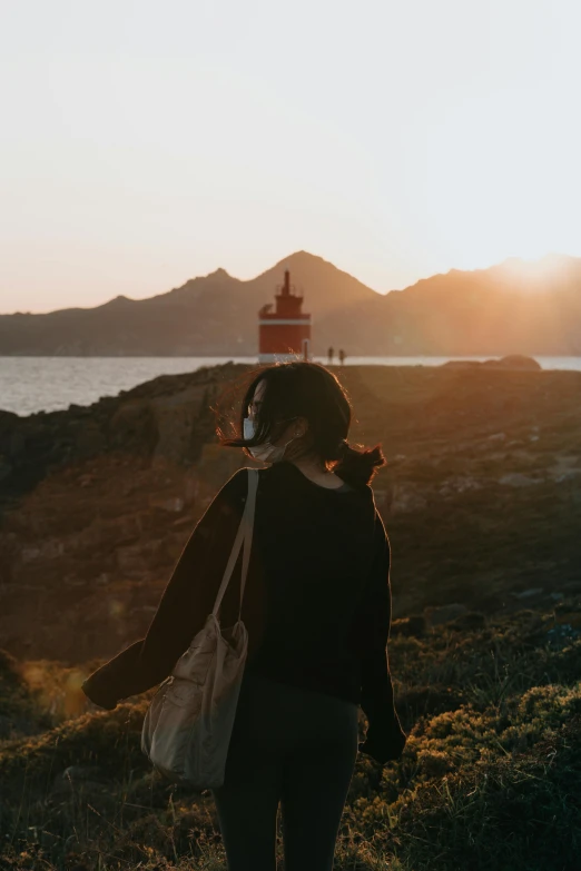 a woman is standing on the edge of a hill at sunrise