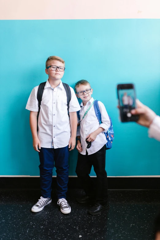 two little boys wearing school uniforms and holding cameras