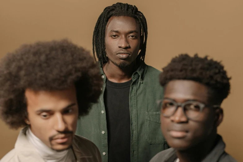 three men, one with afros, pose for the camera