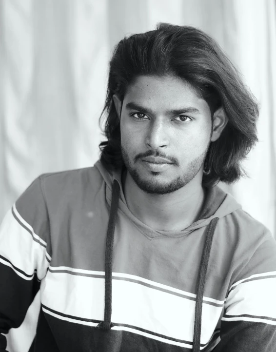 an indian man in striped shirt sitting and looking at the camera