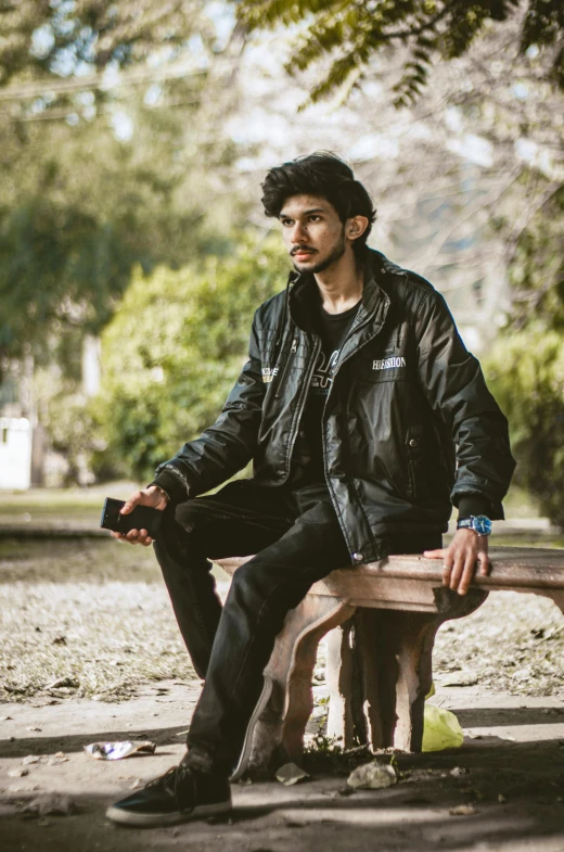 a man in a black jacket sitting on a bench