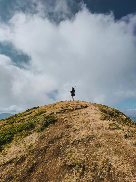 a single person on a hill with a sky background