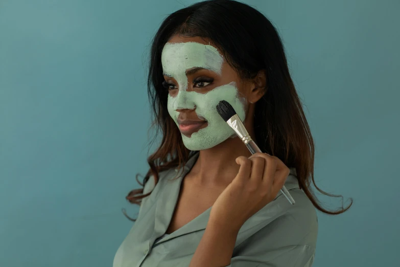 a woman getting her makeup done with green mask