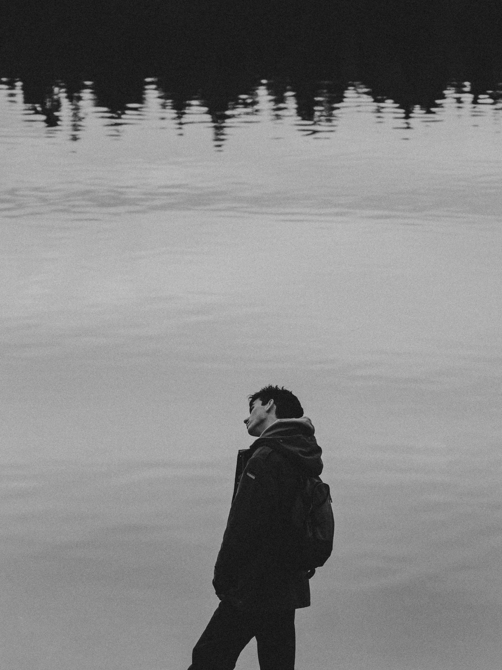 a black and white po of a man standing near a lake