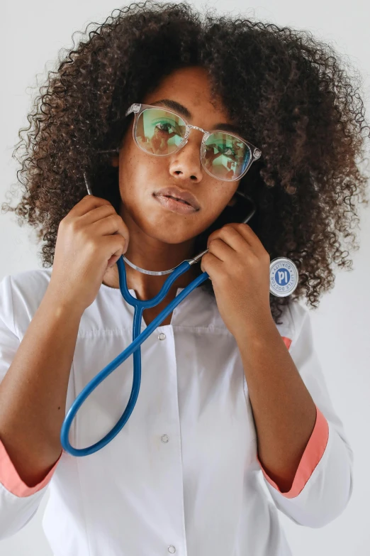 woman with curly hair and green tinted glasses wearing a stethoscope