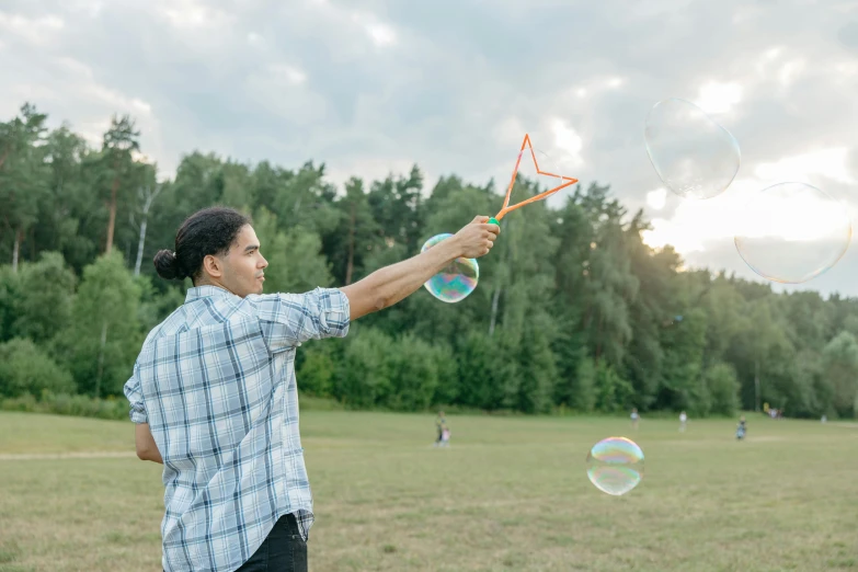 the man is holding up three soap bubbles