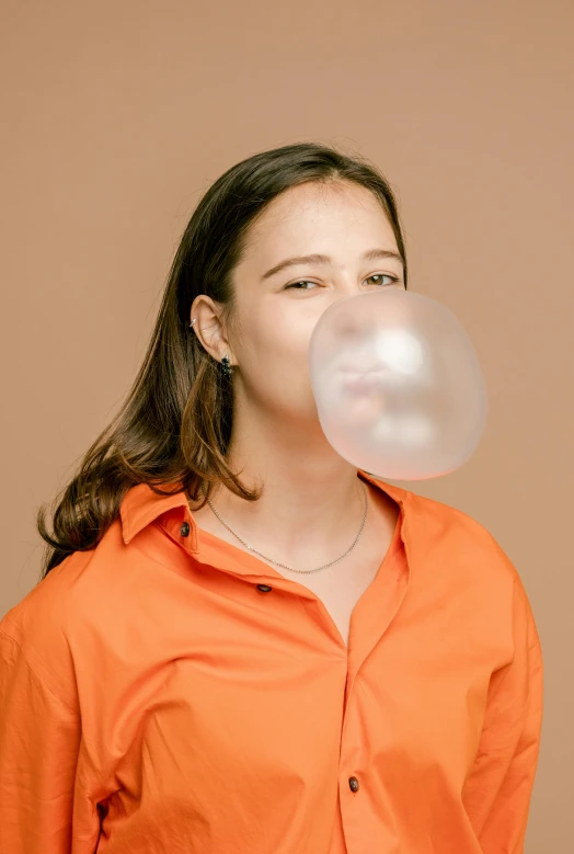 a woman in an orange shirt is blowing bubbles on her nose