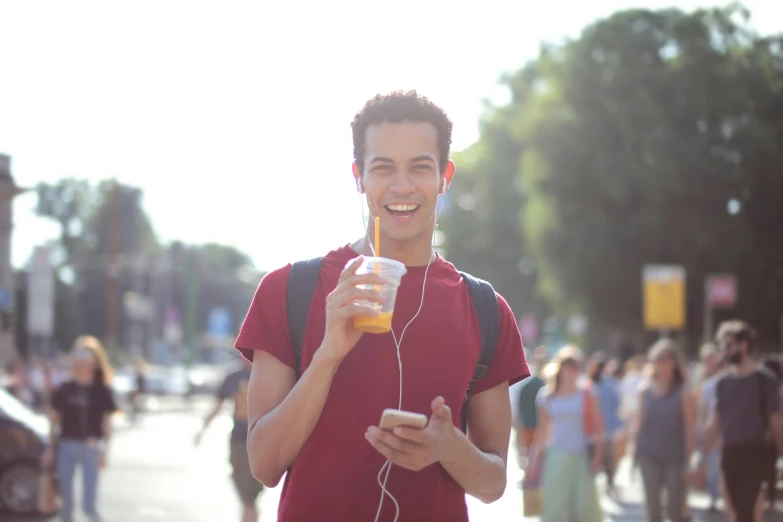 a young man holding up a drink in a crowded street