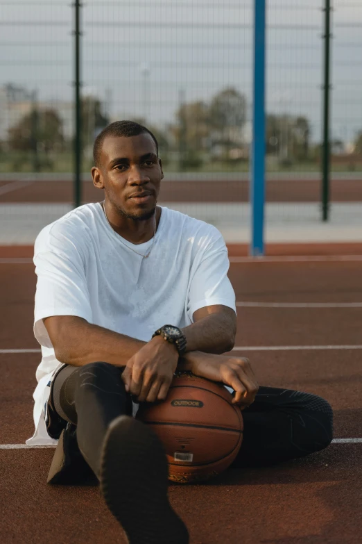 a man sitting on the ground holding a basketball