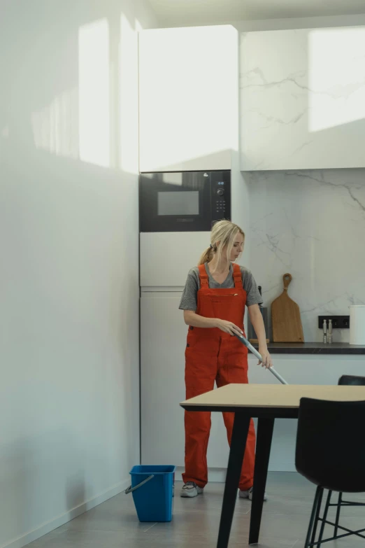 a woman in an orange uniform standing in front of a counter