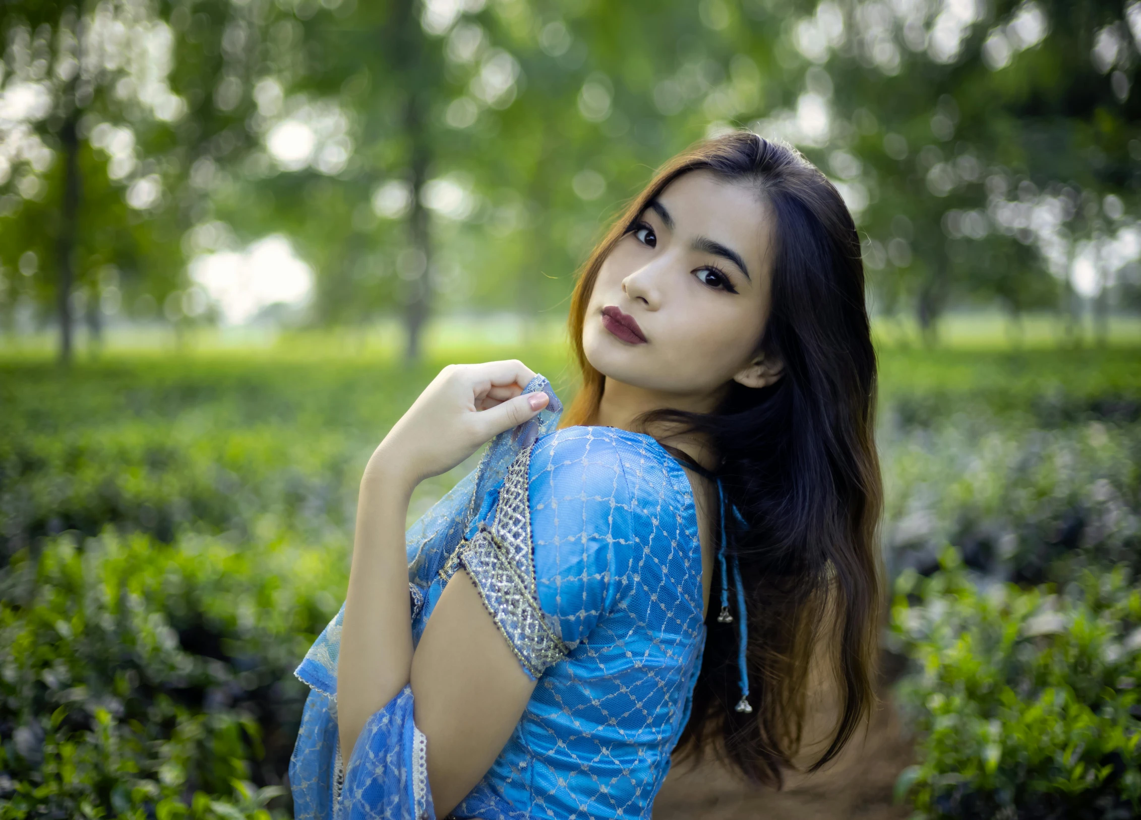 a woman with long hair stands in front of a field