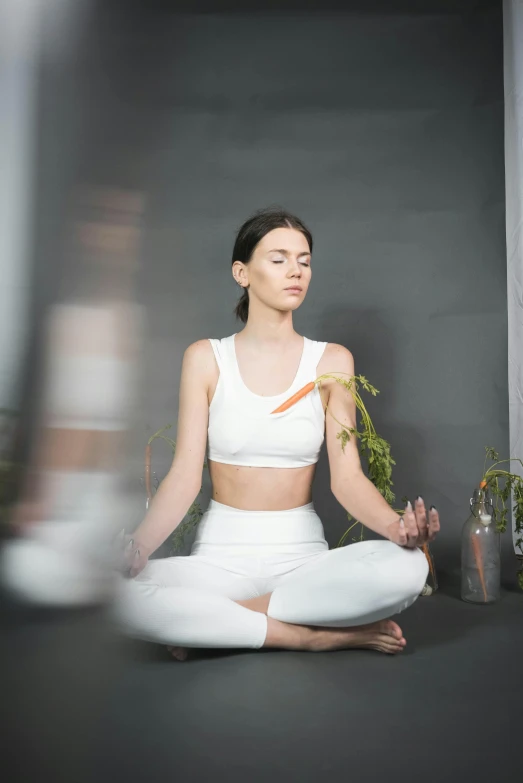 a woman in white sitting on a mat with vegetables