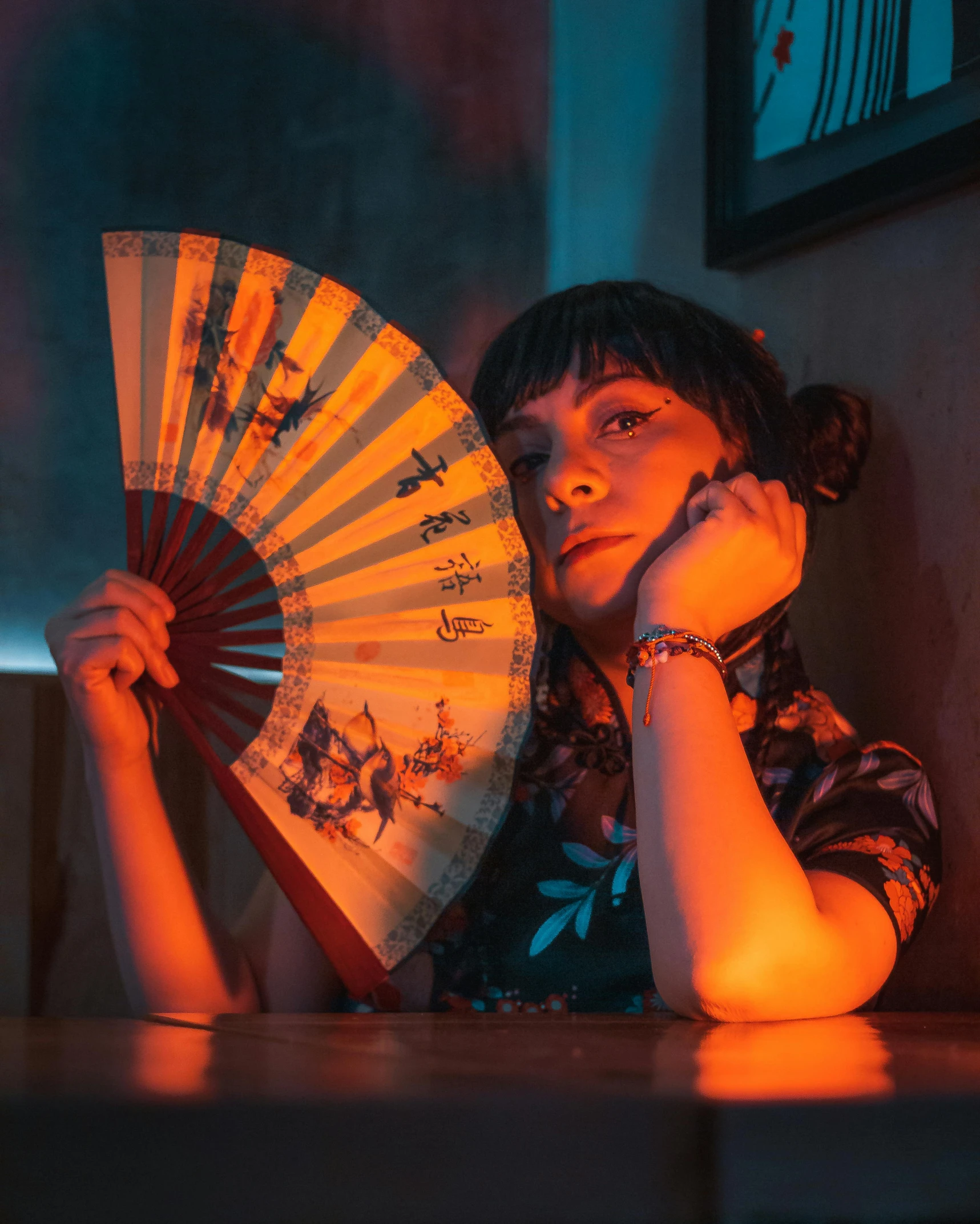 a woman that is holding a fan next to her face