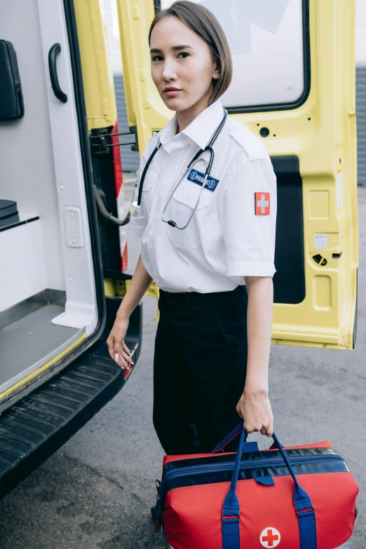 woman in uniform carrying duffle bag on street next to emergency vehicle