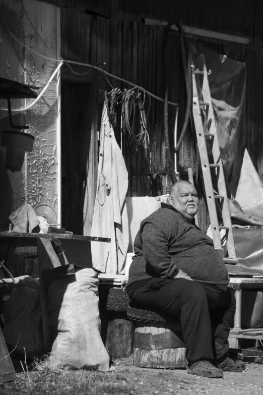 an old man sitting on a wooden bench outside of a house