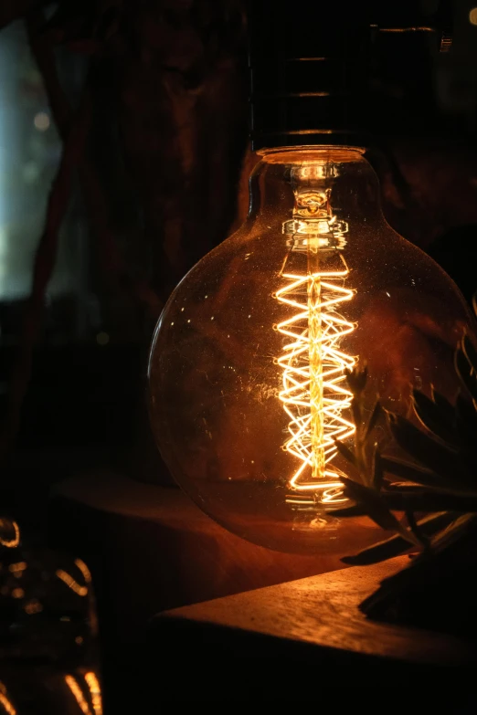 light bulb sitting on table in dark room with person behind it