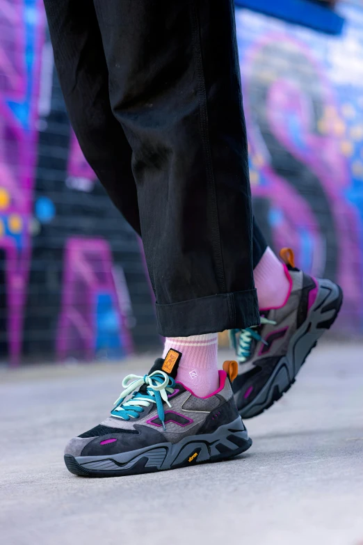 a person wearing colorful sneakers standing on cement
