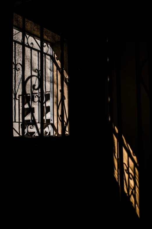 a window in the shadows of a metal gate