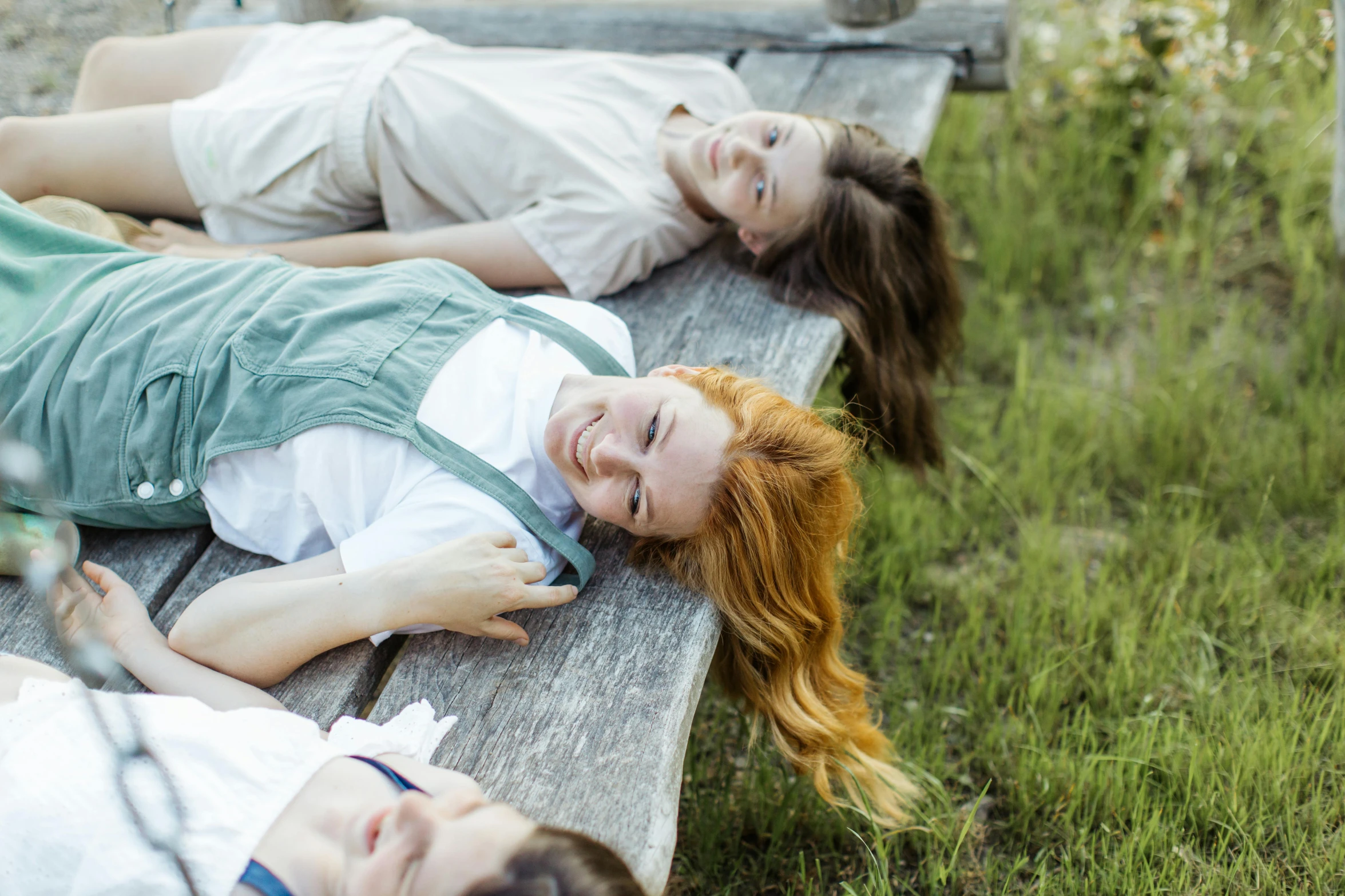 two girls laying on the bench in the grass